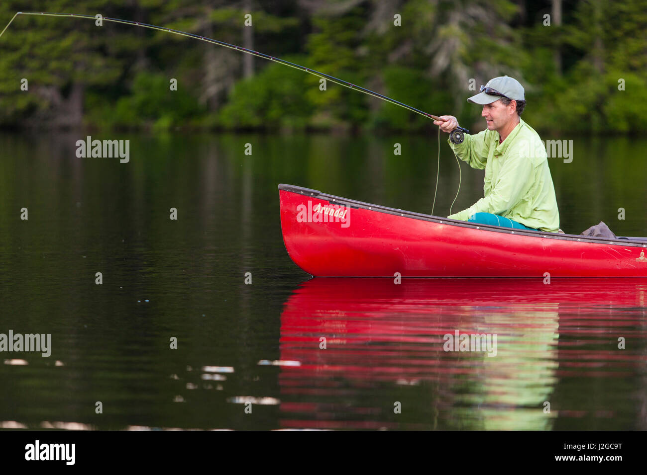 A man flyfishing for brook trout from a canoe on Lang Pond in Maine's