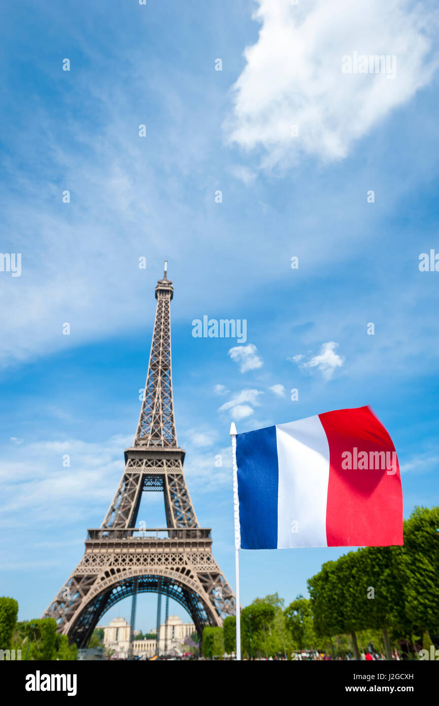 French flag flying in bright blue sky in front of the Eiffel Tower in Paris, France on a spring day Stock Photo
