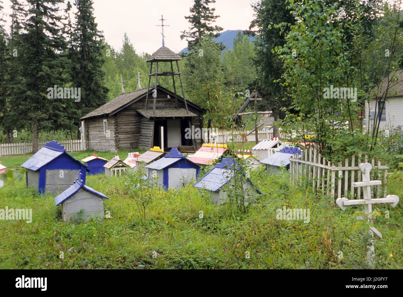 Historic log chapel in sits among painted house grave markers at the