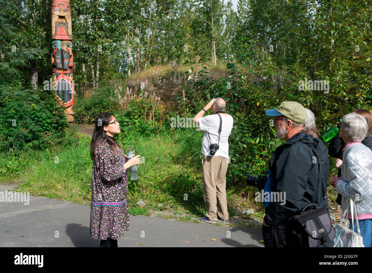 Native interpreter explaining a traditional totem pole to visitors