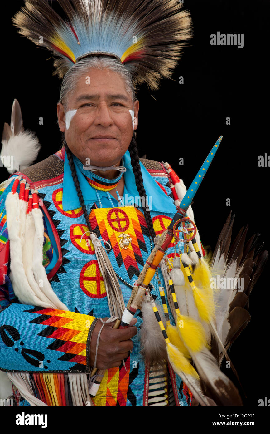 Norman Largo (Dine aka Navajo) dressed in colorful men's traditional dance clothing and roach headdress holds an eagle wing fan and beaded dance stick Stock Photo