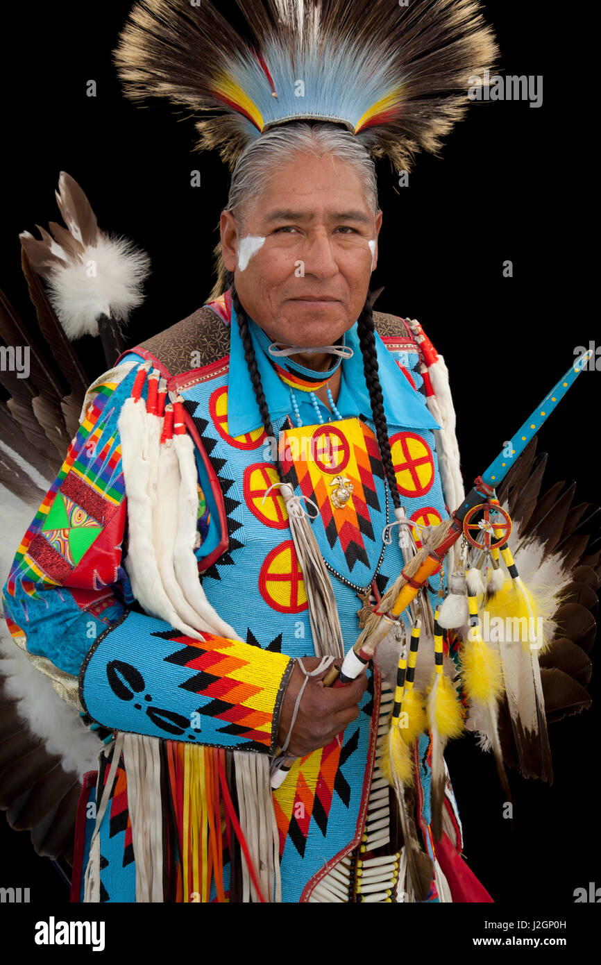 Norman Largo (Dine aka Navajo) dressed in colorful men's traditional dance clothing and roach headdress holds an eagle wing fan and beaded dance stick Stock Photo