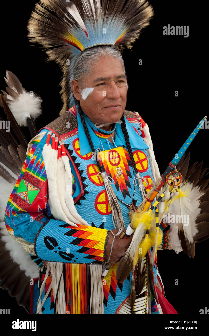 Norman Largo (Dine aka Navajo) dressed in colorful men's traditional dance clothing and roach headdress holds an eagle wing fan and beaded dance stick Stock Photo