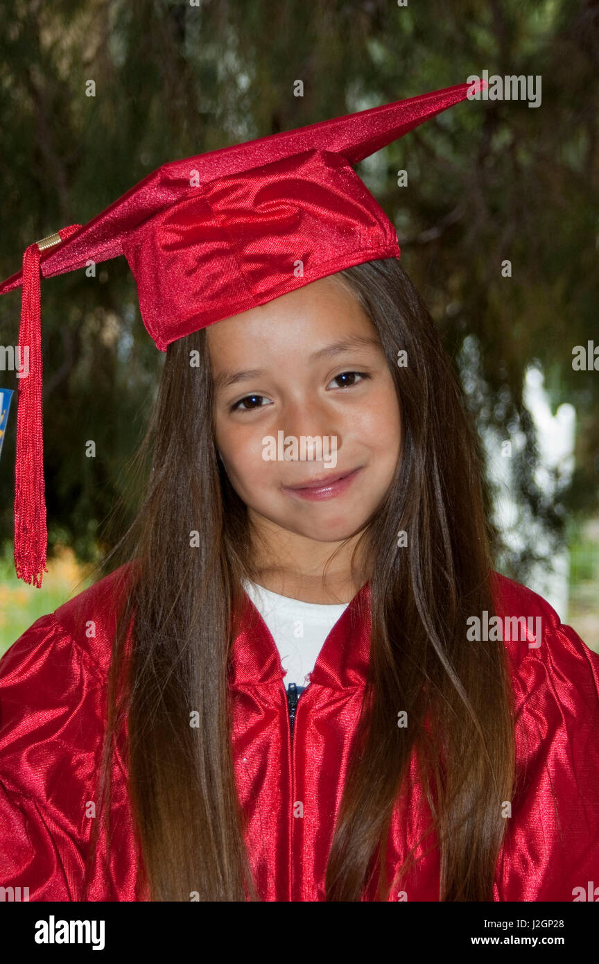 Native American elementary age child dressed in cap and gown during a graduation ceremony for passing her grade at school. Stock Photo