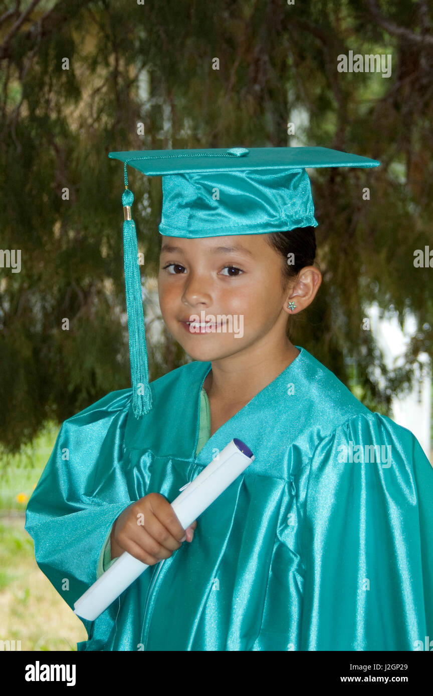 Native American elementary age girl dressed in graduation cap and gown  holds up her diploma for passing her grade Stock Photo - Alamy