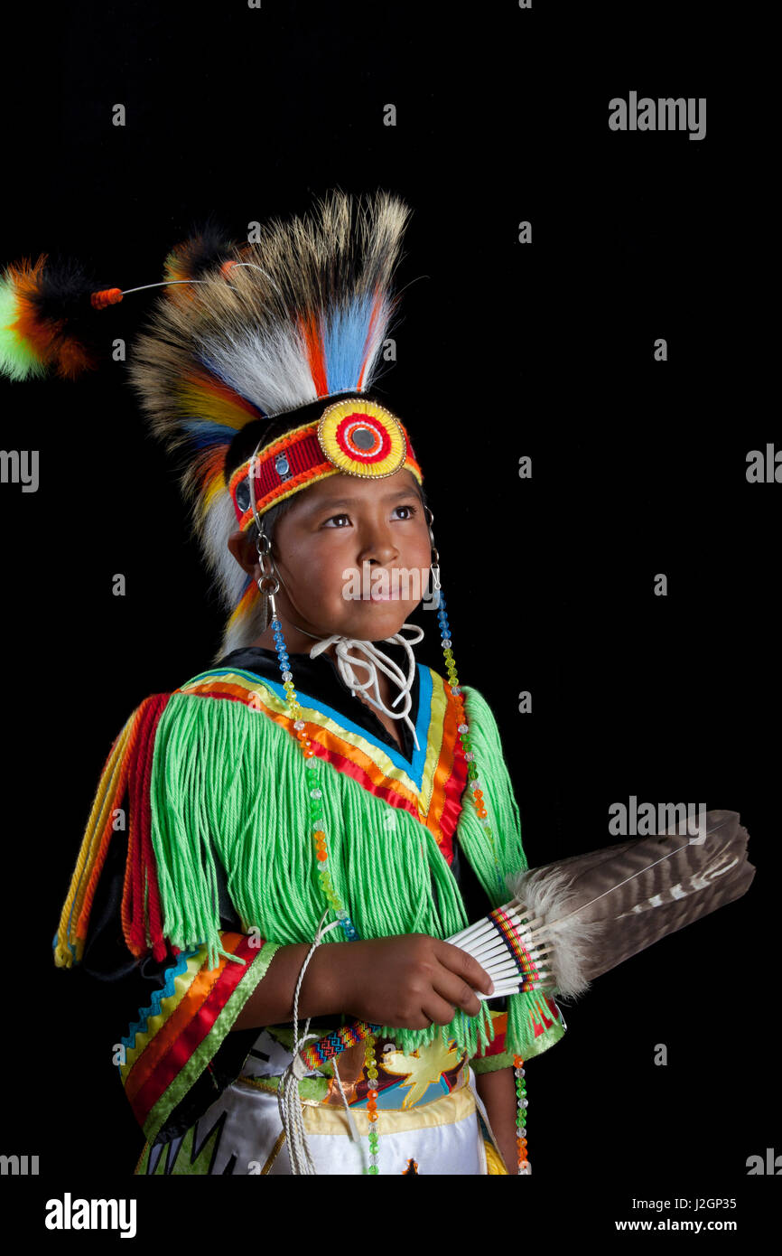 10 years old Thomas Tom (Temoke-Shoshone) dressed in colorful grass dancer outfit and roach headdress with black background Stock Photo