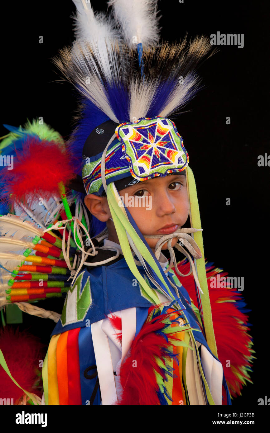 Elementary age Native American boy dressed in colorful fancy dancer pow wow regalia against a black backdrop during the Sho-Ban Indian Festival, Fort Hall Idaho. Flair Popetsaitke six years old (Cheyenne-Kiowa) Stock Photo