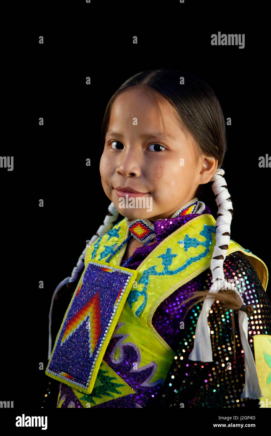 Kelci Etsitty (Dine aka Navajo) 8 years old dressed in traditional colorful pow wow dance regalia and braid wraps with black backdrop Stock Photo