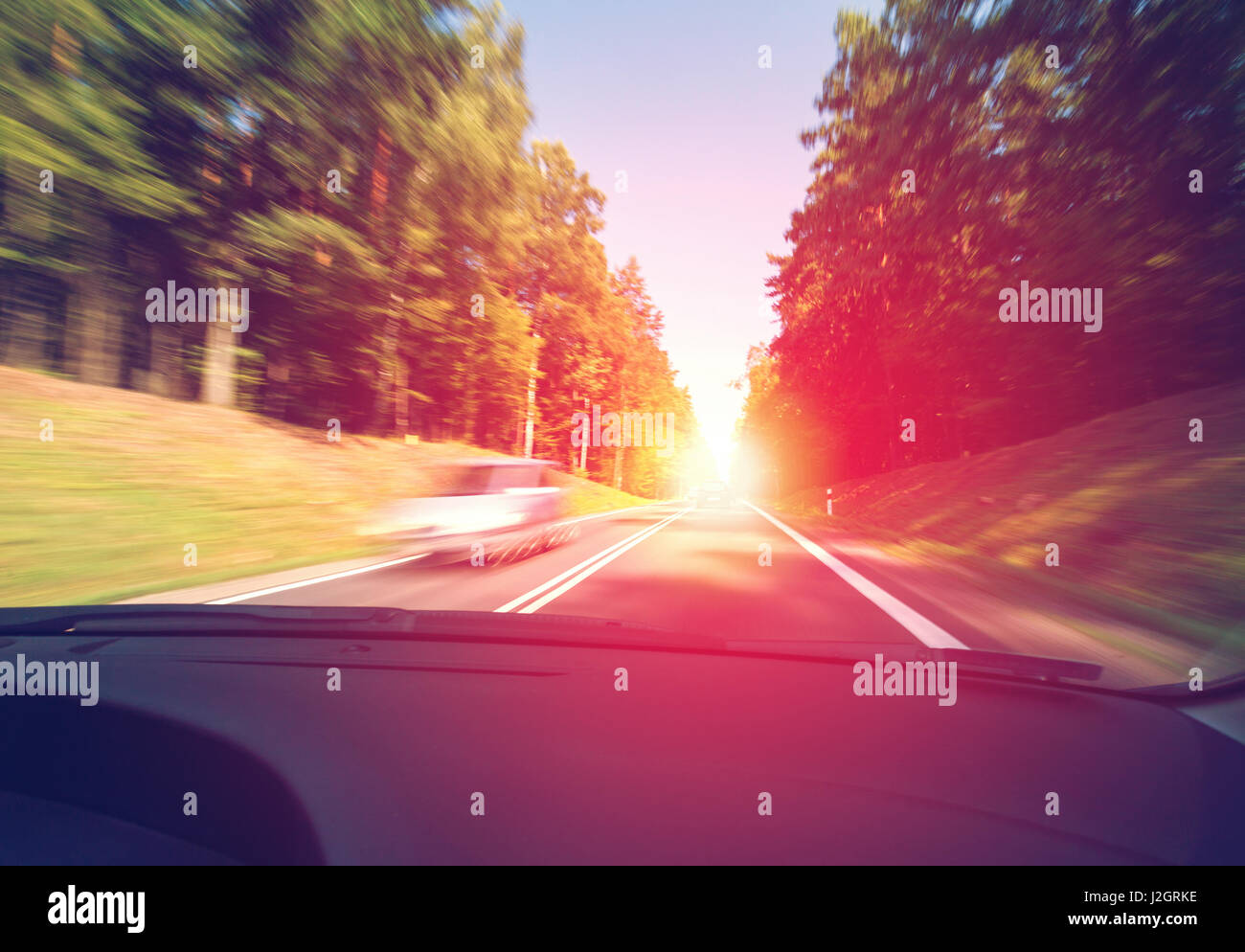 Driving a car in the morning to the sunrise in good weather conditions Stock Photo