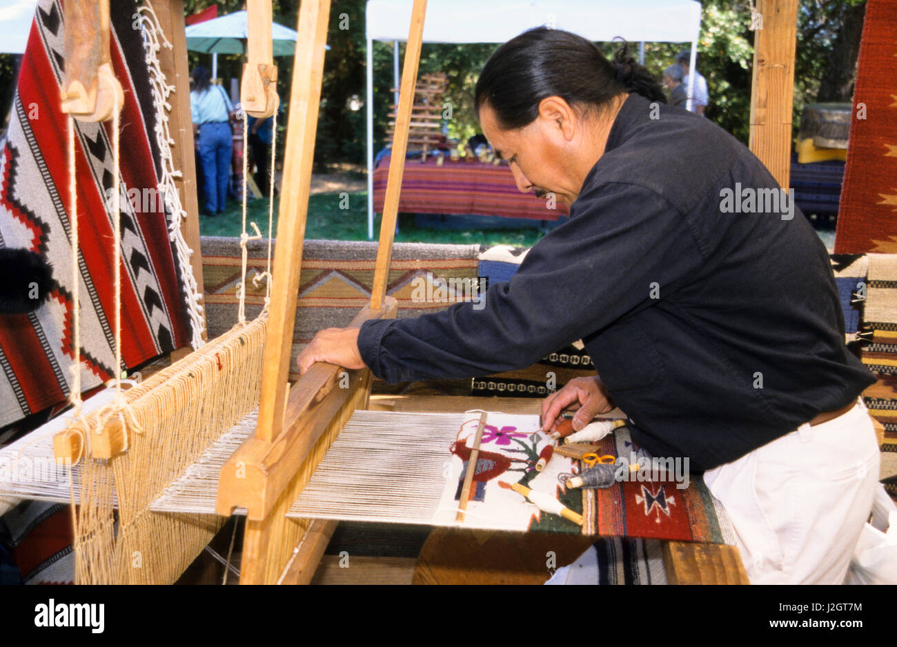 Aztec man demonstrates the use of a wooden weaving loom to make an Aztec pattern on a wall hanging. Stock Photo