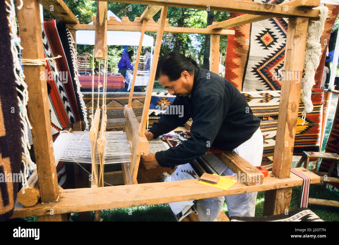 Aztec man demonstrates the use of a wooden weaving loom to make an Aztec pattern on a wall hanging. Stock Photo