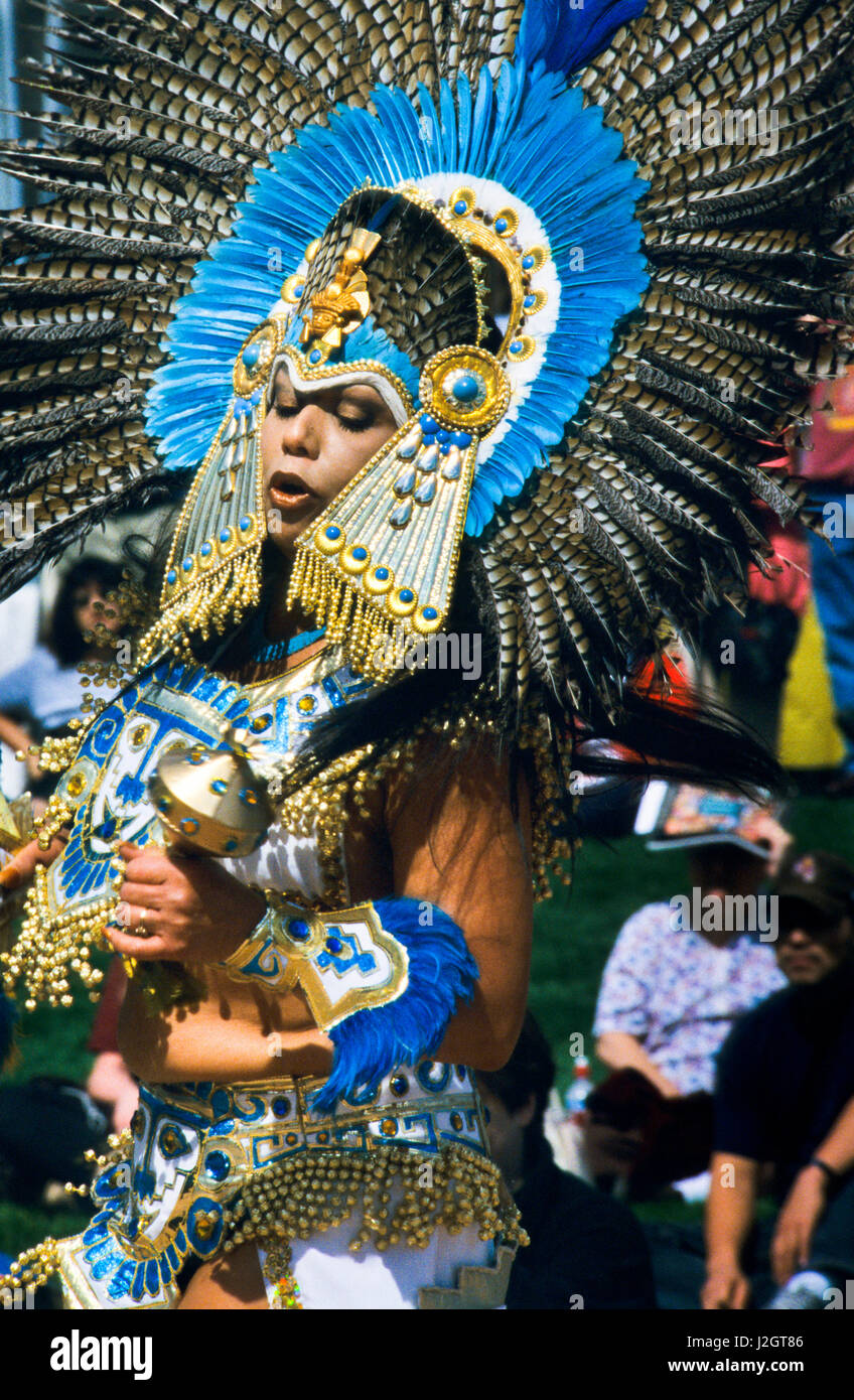 An Aztec woman dressed in an elaborate traditional outfit and large feather headdress shakes a jeweled rattle during a celebration of traditional Aztec dances. Stock Photo