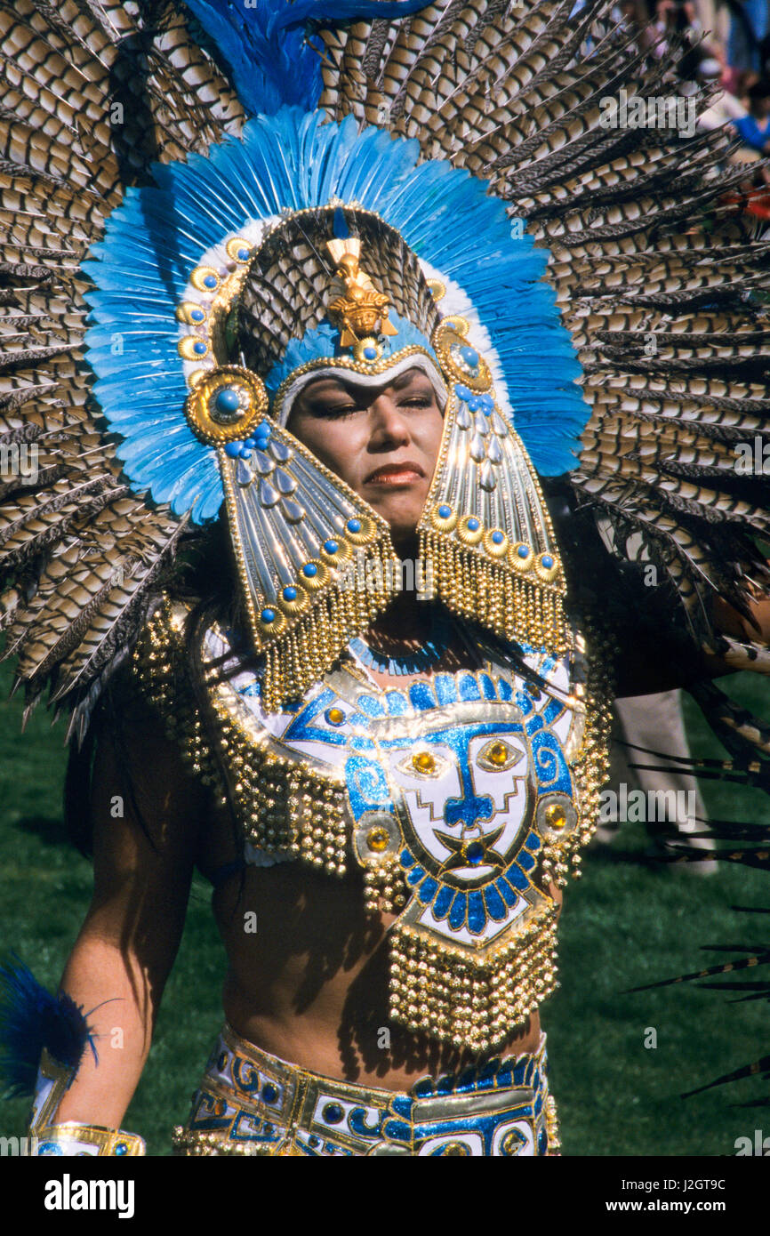 Aztec woman wears a magnificent traditional golden headdress and chest mantle made with blue stones and blue exotic bird feathers Stock Photo