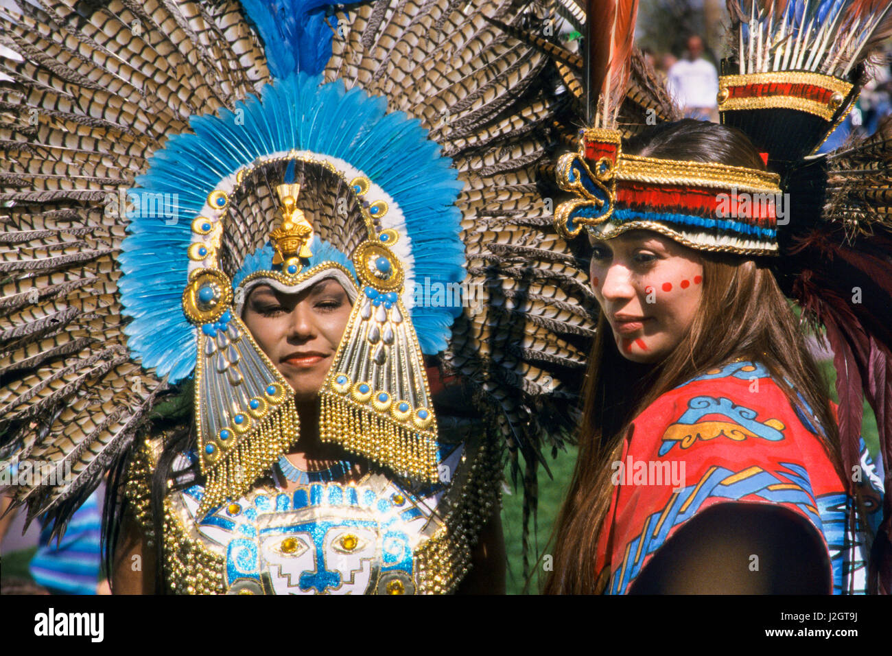 Close-up of two Aztec women dressed in magnificent traditional Aztec regalia and headdresses pose during a ceremonial dance presentation. Stock Photo