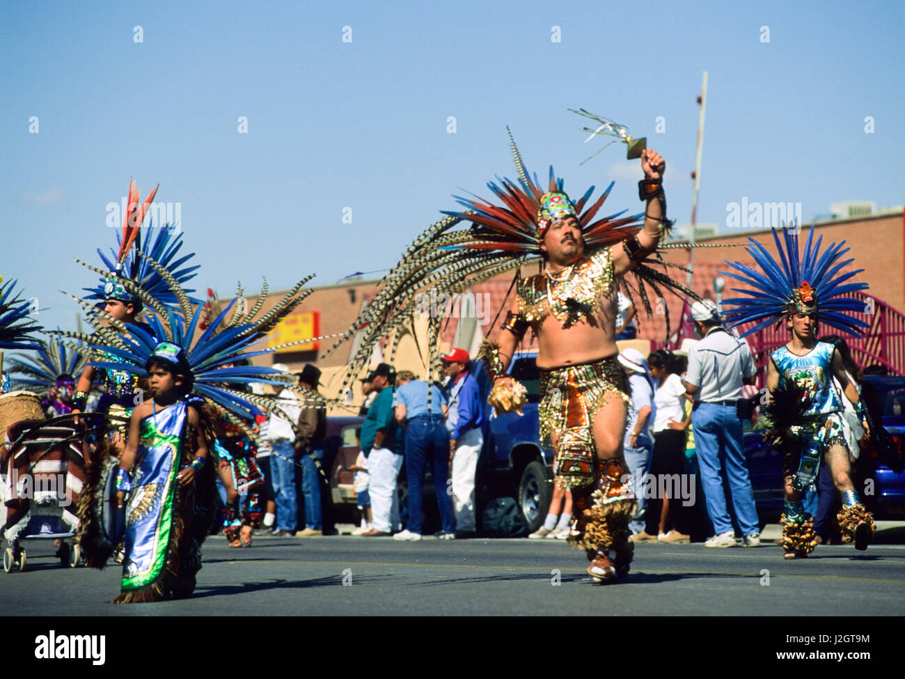 Aztec man with children wear traditional large headdress made from long colorful feathers during an Inter-tribal parade in Gallup New Mexico Stock Photo