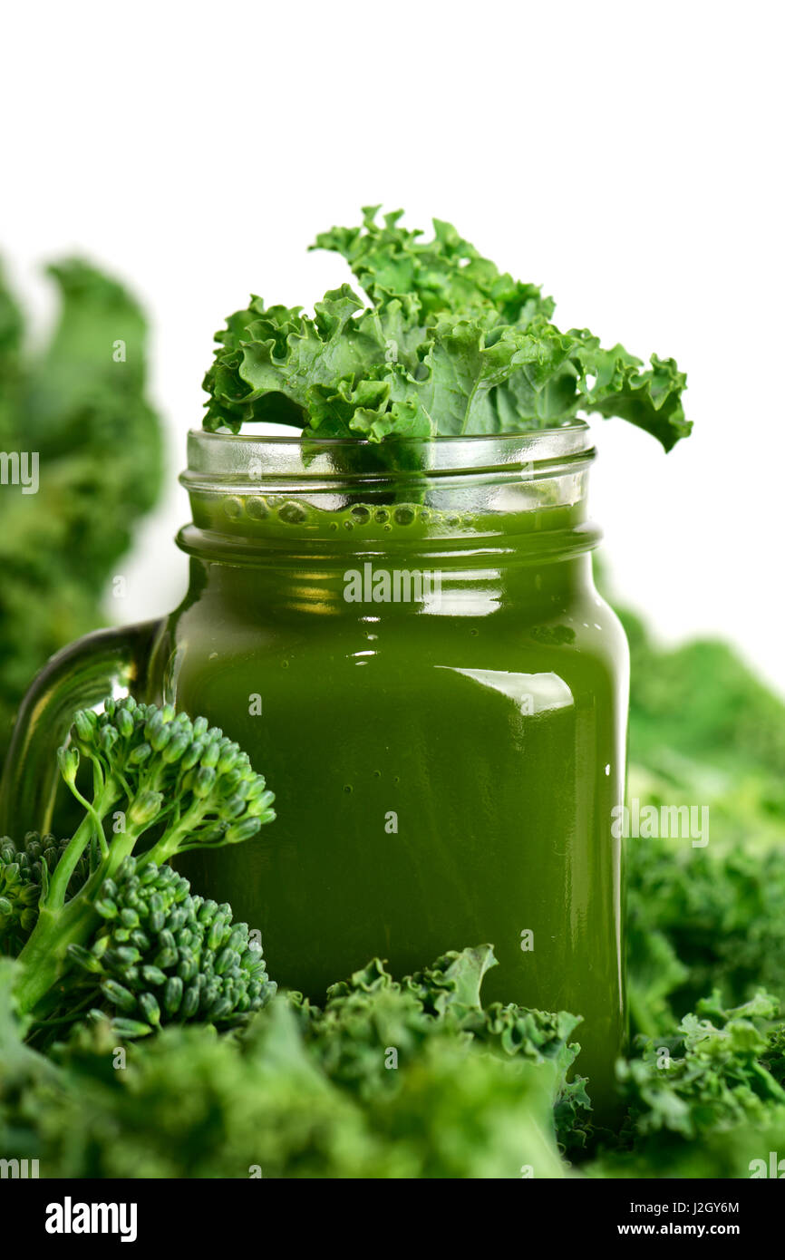 a green smoothie served in a glass mason jar surrounded by some leaves