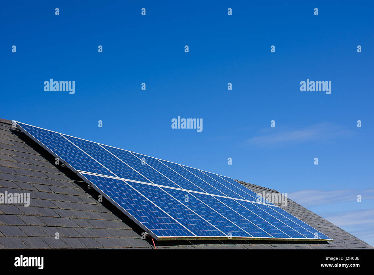 Solar panels on house roof with blue sky in background,North Wales,Uk.Solar power,renewable energy source,environmental friendly energy production,Uk. Stock Photo