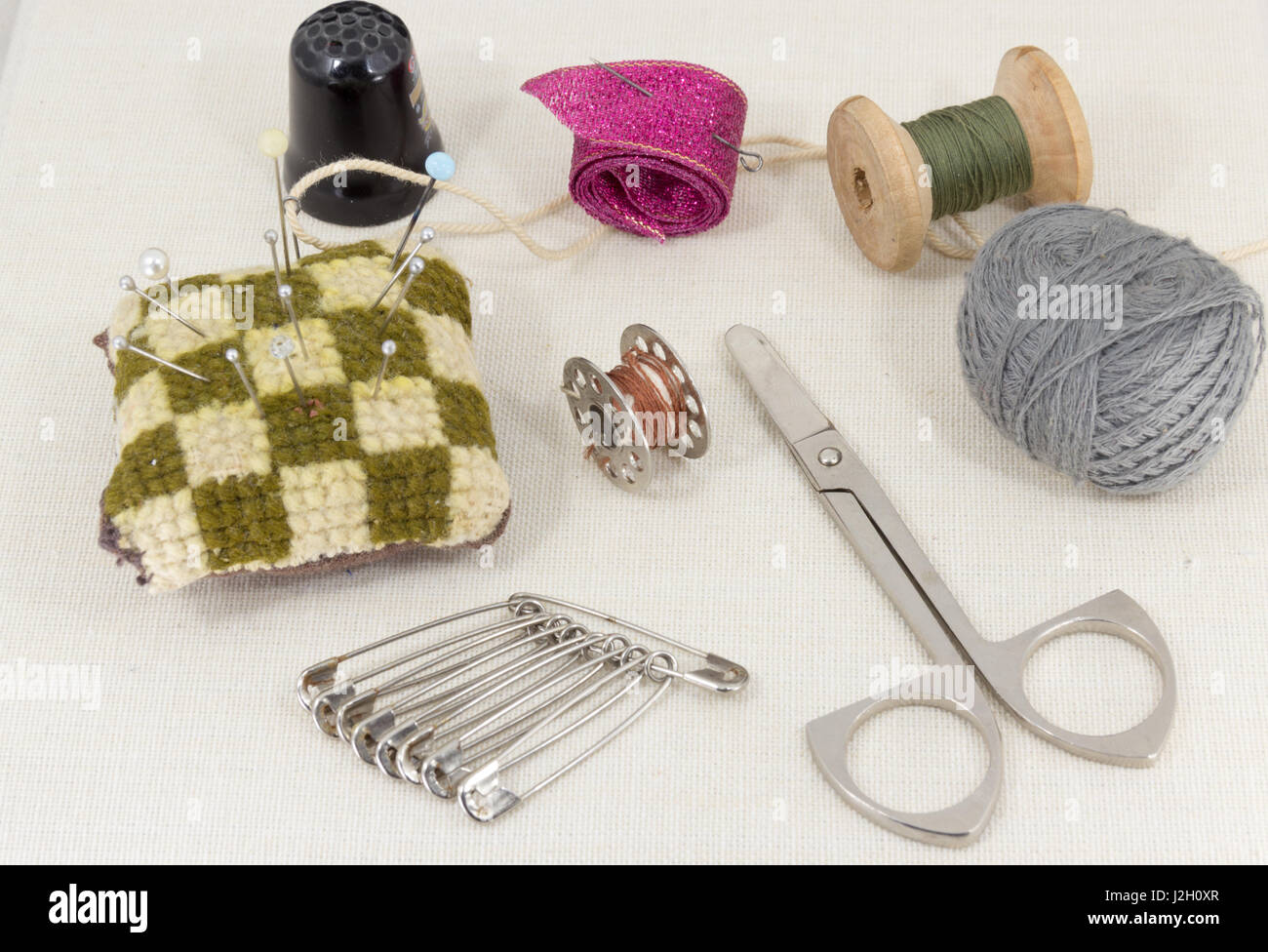 Textile fabric for sewing,accessories for needlework on new textile background. Spool of thread, scissors, thimble, tapemeasure , sewing supplies. Set Stock Photo