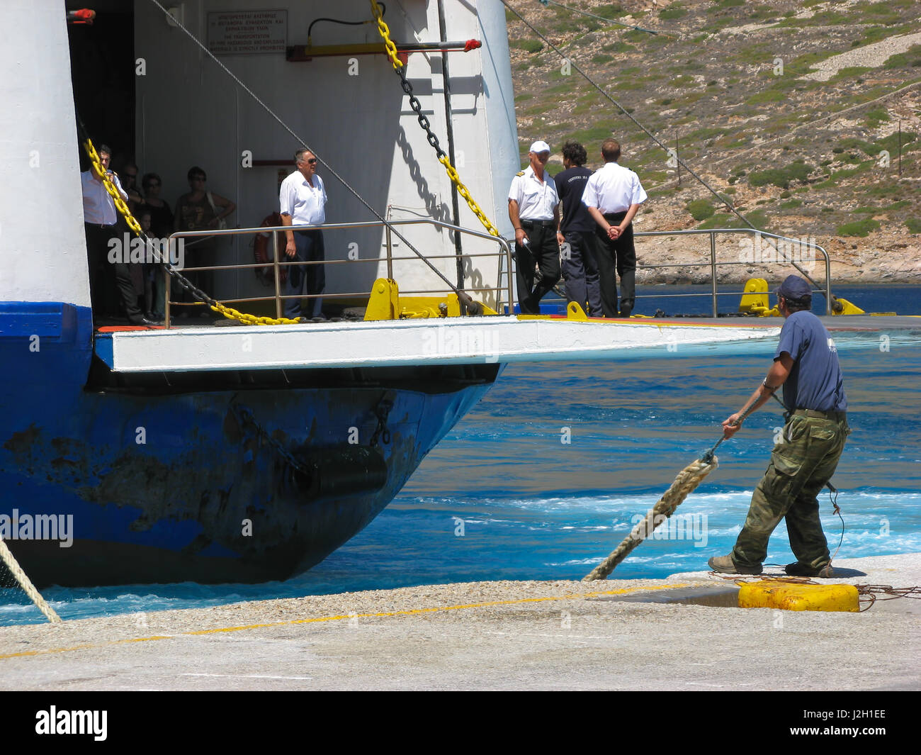 Dock worker A man is pulling a rope while ship crew is standing on a