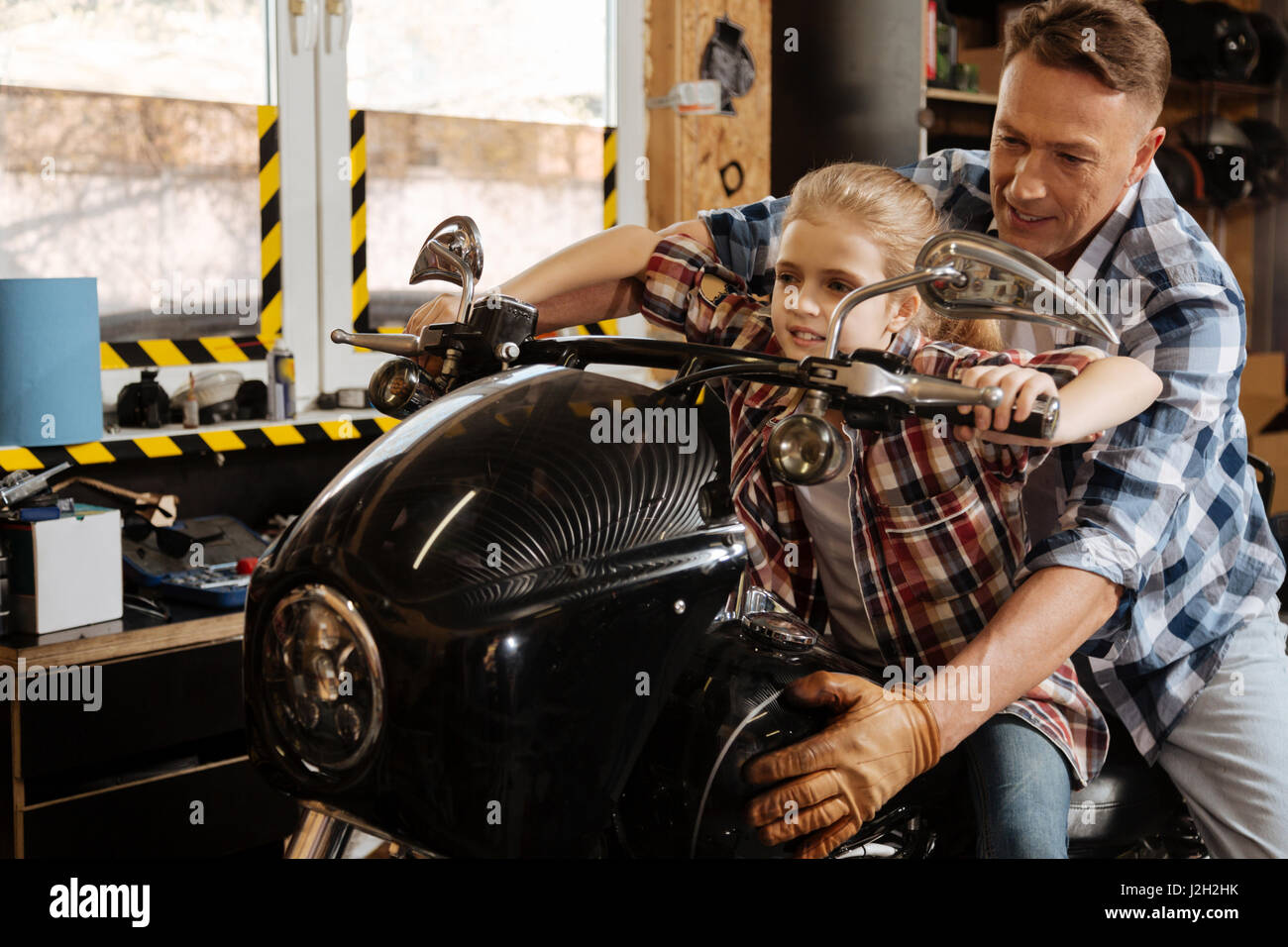 Sit tight. Protective loving handsome father holding a bike and his child while she imagining herself taking a real ride Stock Photo