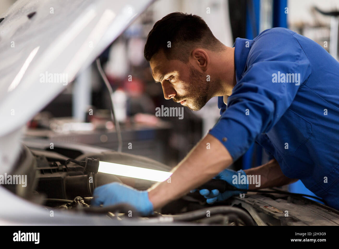 mechanic man with lamp repairing car at workshop Stock Photo - Alamy