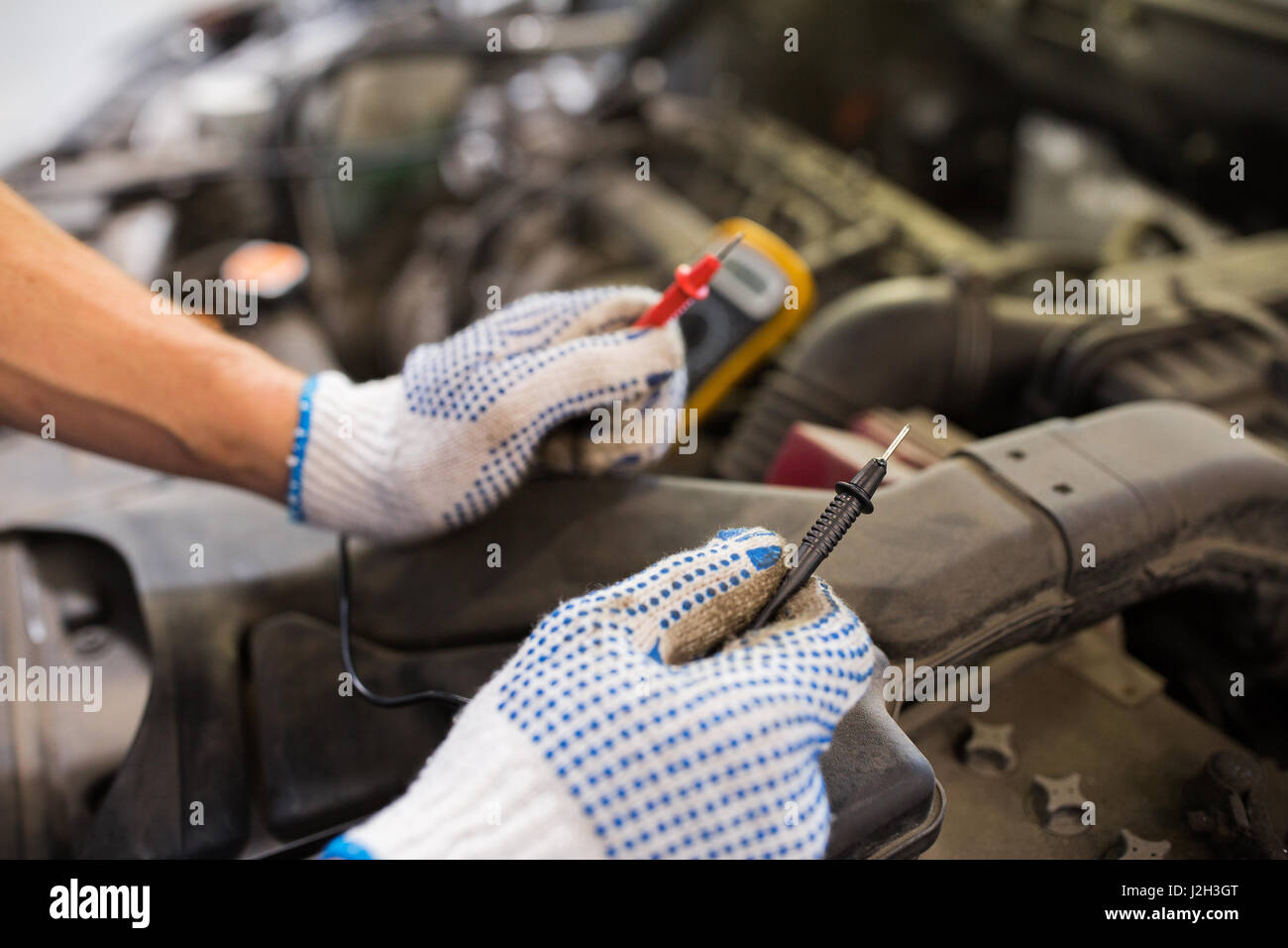 auto mechanic man with multimeter testing battery Stock Photo