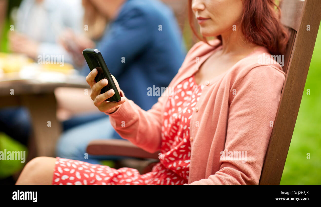 woman with smartphone and friends at summer party Stock Photo