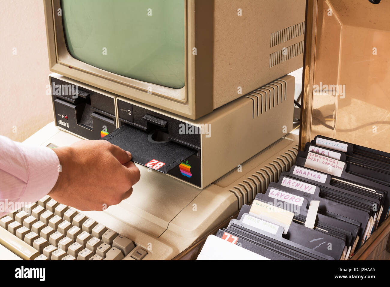 Aged Apple computer and hand insert floppy inside Stock Photo