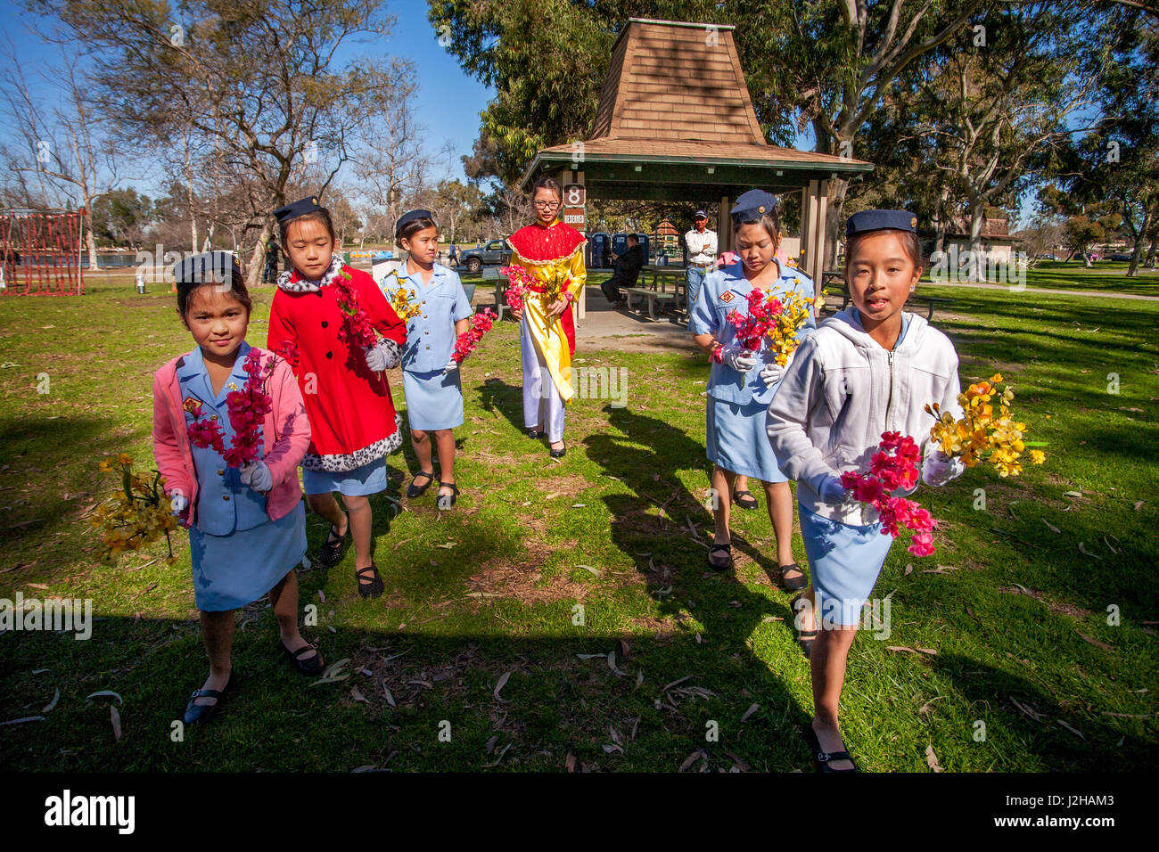 Vietnamese American girls in Ao Dai costumes dance to celebrate the Lunar New Year or Tet in a Fountain Valley, CA, park. Stock Photo