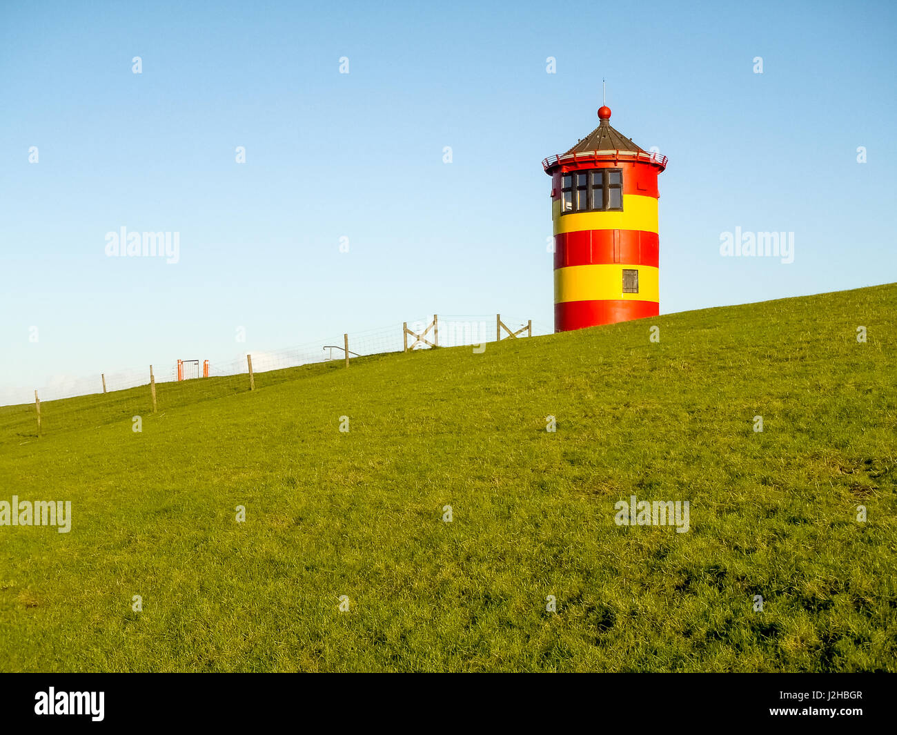 Pilsum, Germany - December 6, 2014: Lighthouse located near the coast especially for its colors in yellow and red stripes. It is located on a barrier  Stock Photo