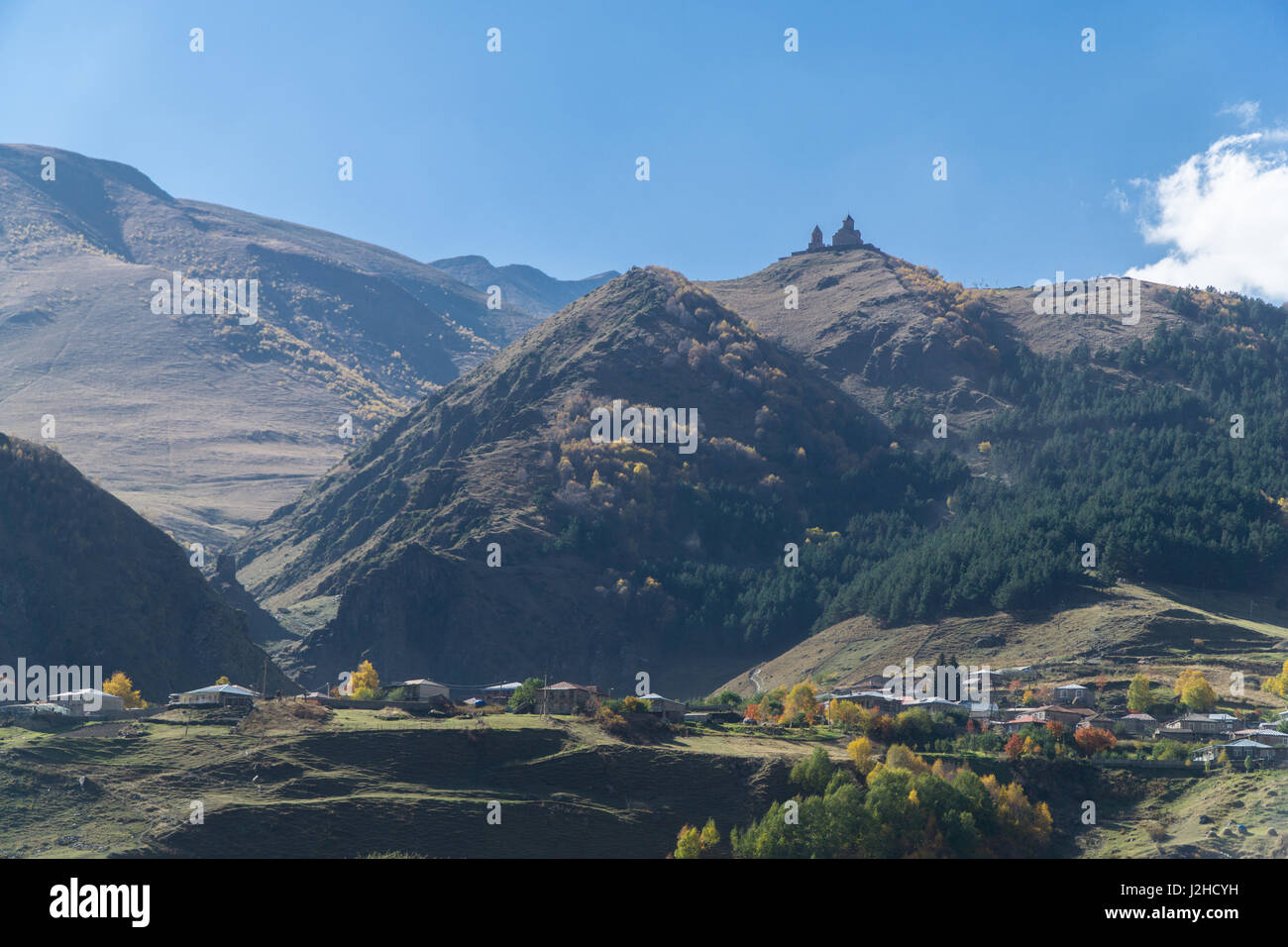 View of village Stepantsminda and Gergeti Trinity Church in sunny weather in september Stock Photo