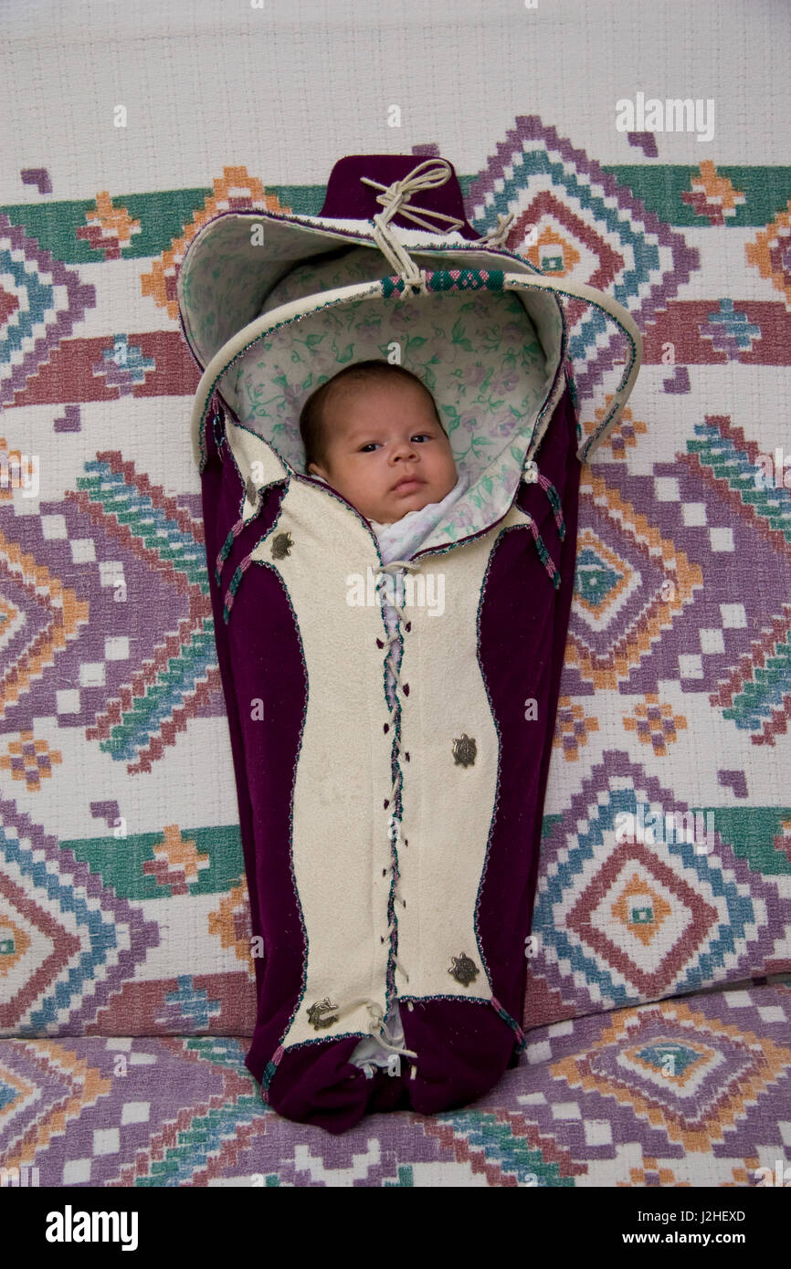 Newborn baby bundled and wrapped inside of a traditional cradleboard of the Plateau Salish Kootenai Tribe also known as the Flathead. (MR) Stock Photo