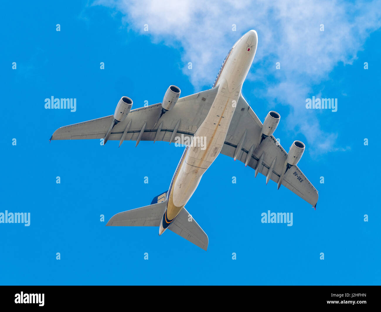 Jet passenger plane against blue sky with clouds seen from below. Stock Photo