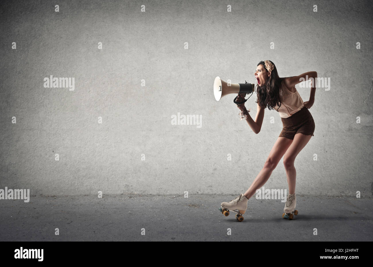 Woman in rollerskates with megaphone Stock Photo