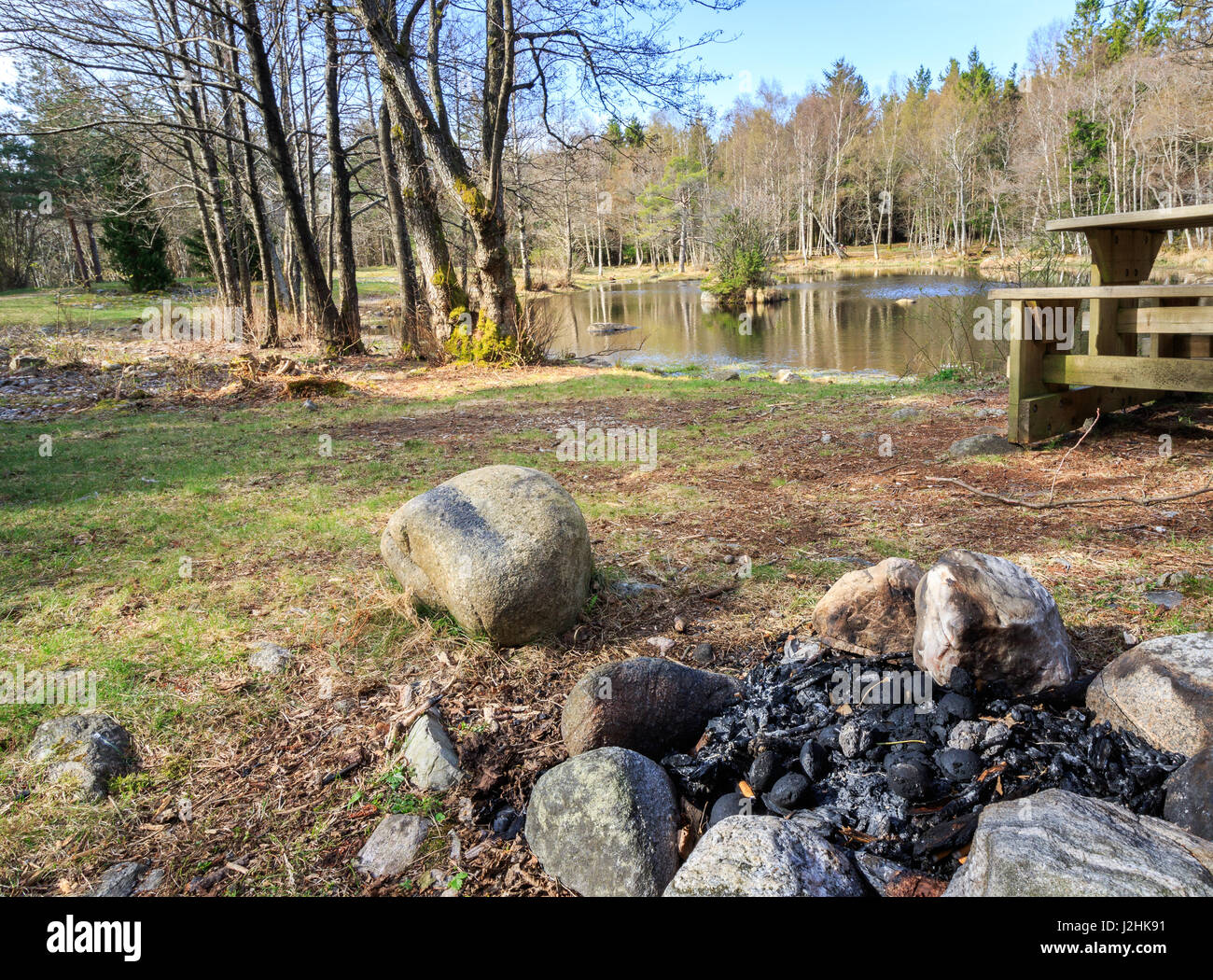 Small lake with campfire and bench in Jomfruland National Park, Kragero, Norway. Jomfruland, meaning Virgin Land in Norwegian, is part of Raet, a big  Stock Photo