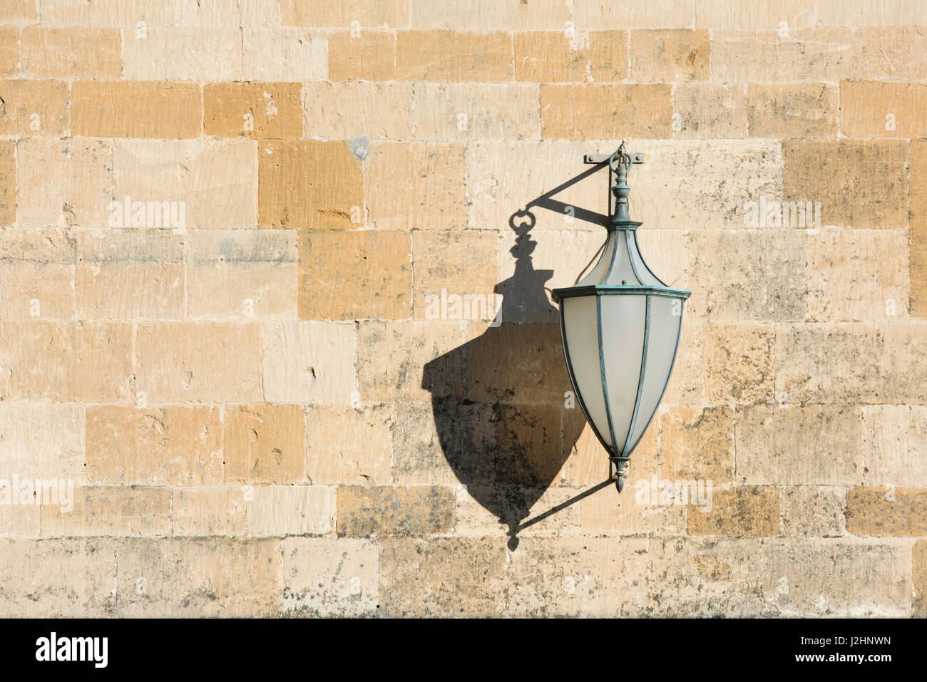 Old Street lamp and shadow on Woolstaplers hall cotswold stone wall. Chipping Campden, Cotswilds, Gloucestershire, England Stock Photo