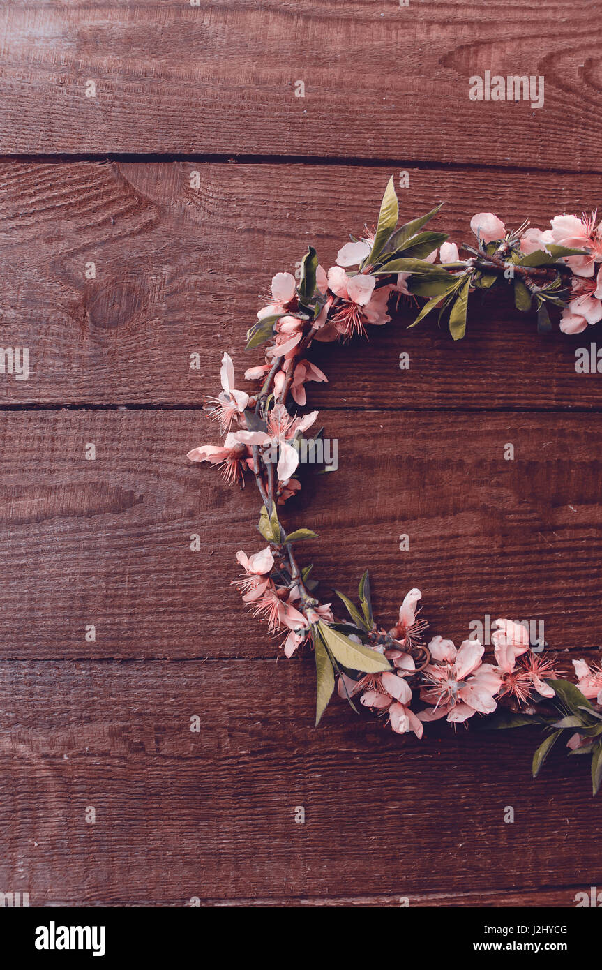 Wreath of peach tree flowers on a wooden table background, photo in retro style Stock Photo