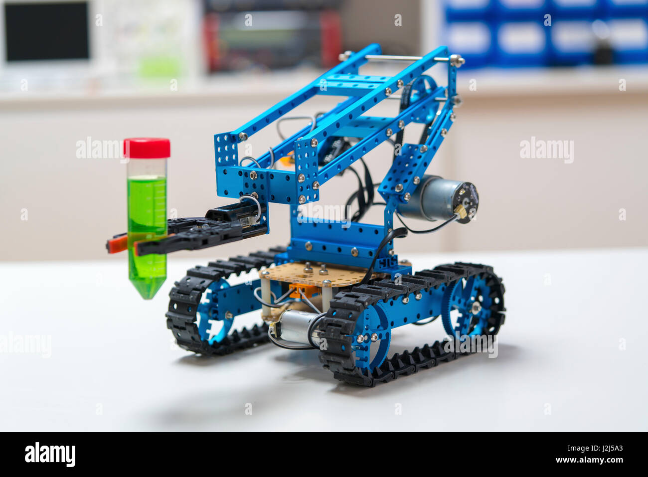 Robotic arm holding test tube on caterpillar tracks. Stock Photo