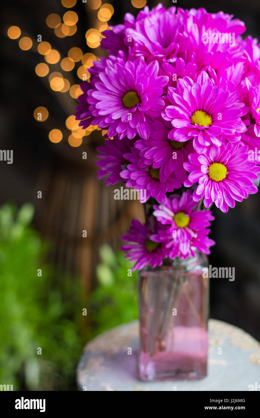 Bright pink floral arrangement with greenery and twinkle lights in the background. Stock Photo