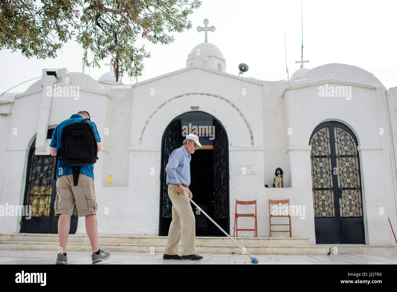 Man sweeping steps in front of a church in Athens, Greece, his dog watches him Stock Photo Alamy
