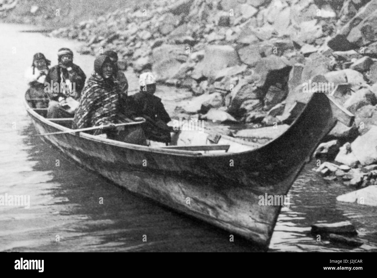 Historic photograph of a Chinook family sitting inside a traditional carved Northwest dugout canoe on the Columbia River, Washington Stock Photo