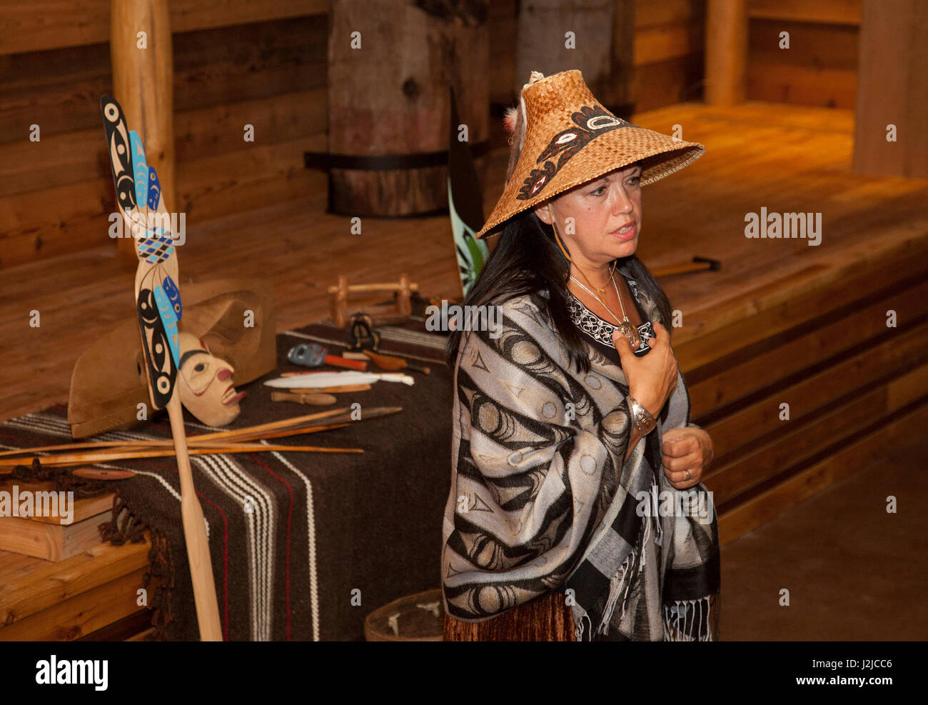 Traditional storyteller dressed in cedar bark hat and wool shawl tells Coast Salish legends handed down from the Tulalip Tribes in the new longhouse located at the Hibulb Cultural Center and Museum. Marysville, WA. Stock Photo