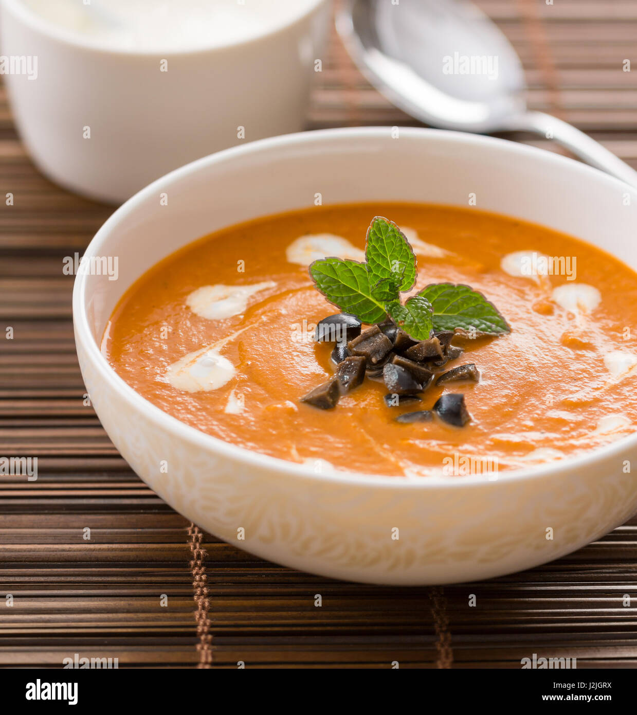 Vegetarian cream soup with eggplant , garnished with cream, olives and mint Stock Photo