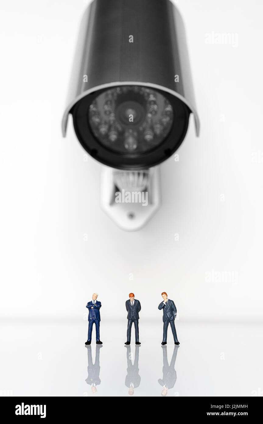 Security camera pointed at three business figurines Stock Photo