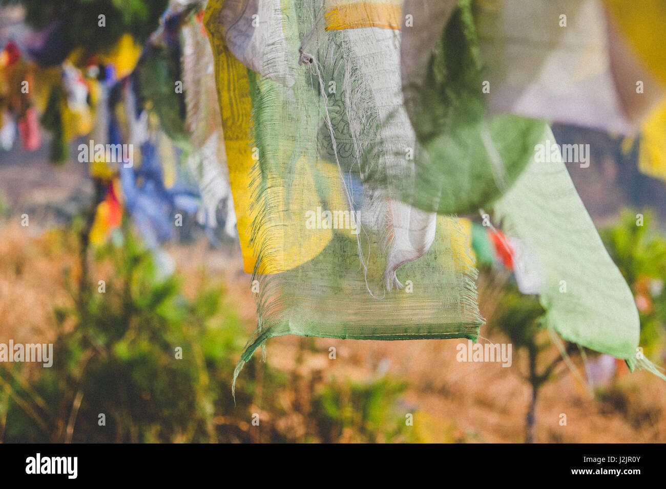 Flapping colourful prayer flags written with mantras are being carried by the wind, sending blessings to all living beings. Stock Photo