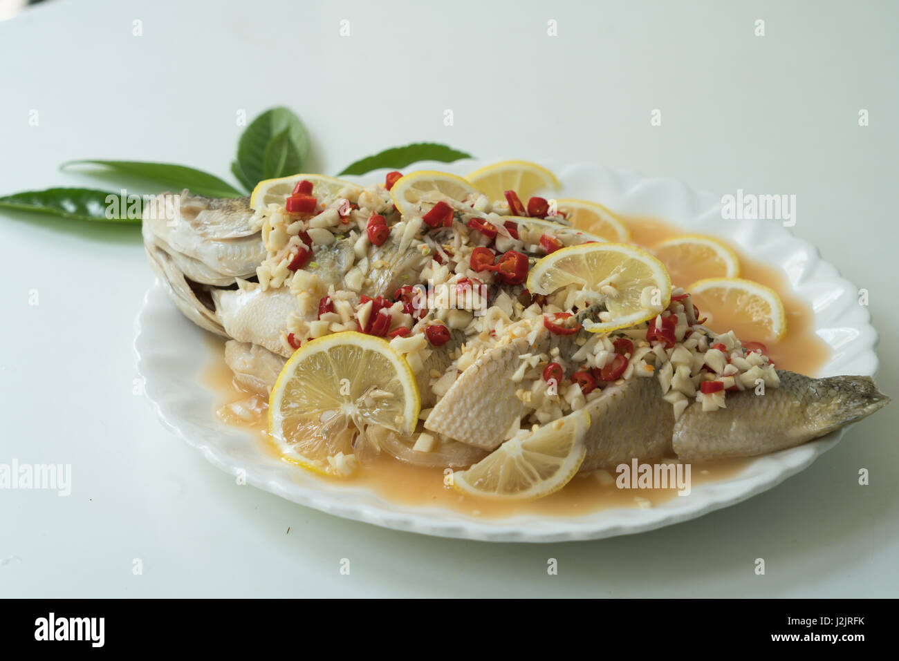 A Seabass steam with lemon, garlic and red chili Thai food, on white
