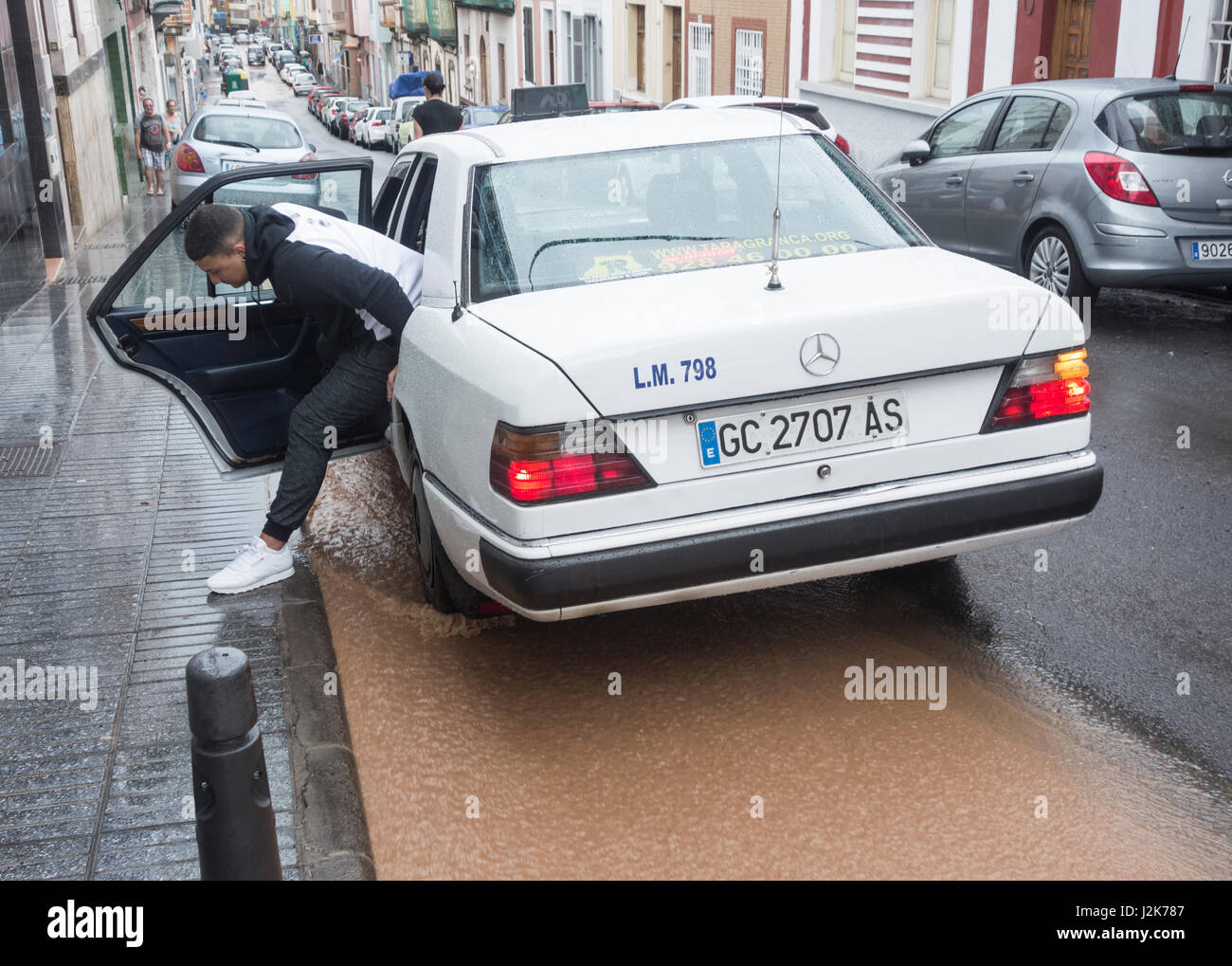 Las Palmas, Gran Canaria, Canary Islands, Spain 29th April, 2017. Weather:  A man getting out of a taxi steps over water pouring down the street in Las  Palmas as torrential rain falls