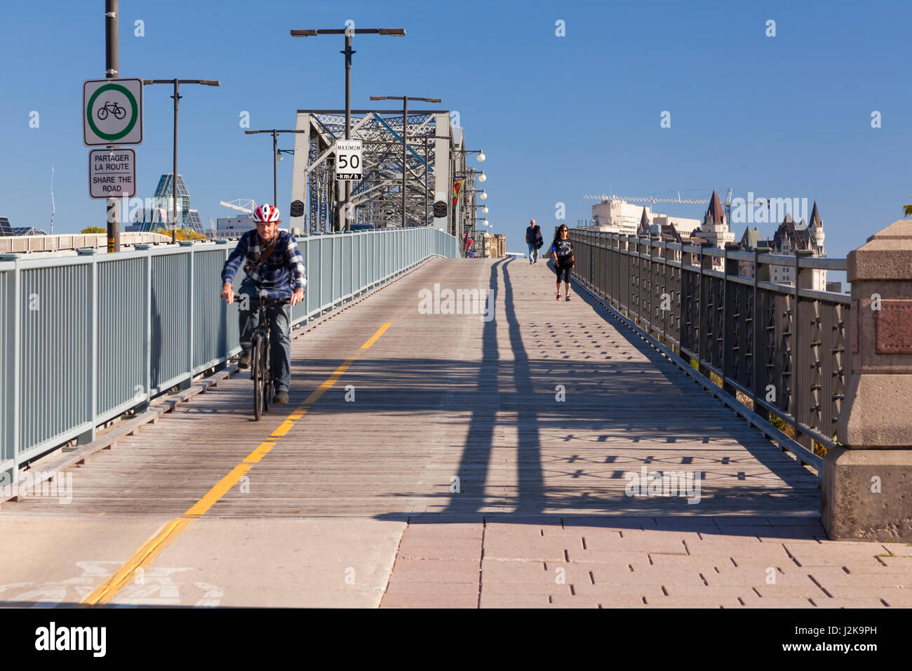 A cyclist and pedestrians crossing the Royal Alexandra Interprovincial Bridge (Alexandra Bridge). Hull, Gatineau, Quebec, Canada. Stock Photo