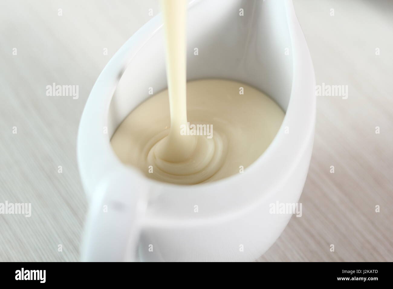 Pouring bechamel white sauce into gravy boat. Making Lasagna Bolognese Series. Stock Photo