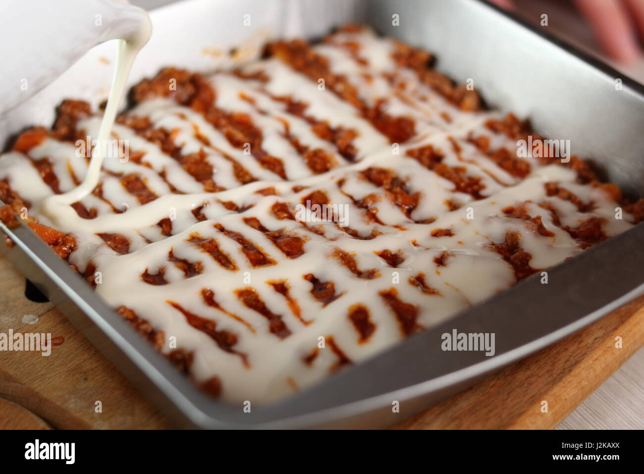 Pouring bechamel sauce onto ground meat layer. Making Lasagna Bolognese Series. Stock Photo